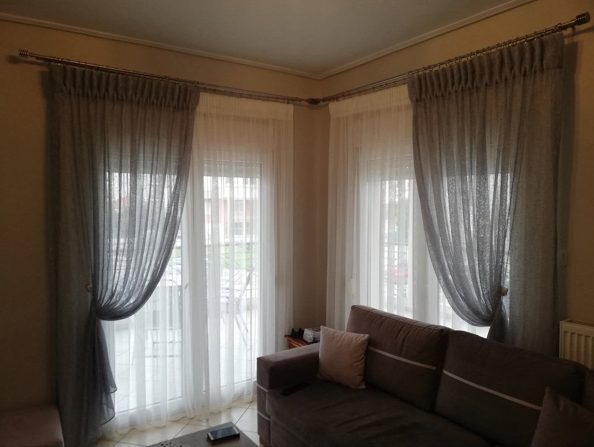 Γωνιακό σαλόνι με γκρι διάφανες κουρτίνες και δέστρες